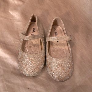 Girl’s gold sequined Mary Jane dress shoes with light blue accents.